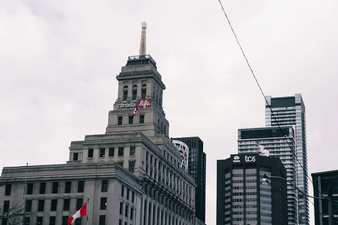 The Canada Life Building tower in downtown Toronto, Ontario, surrounded by modern city architecture against an overcast sky.