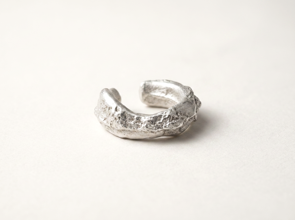 Handgegossener Regolith Earcuff aus Silber/Gold mit rauer, organischer Oberflächenstruktur am Ohr gestylt.