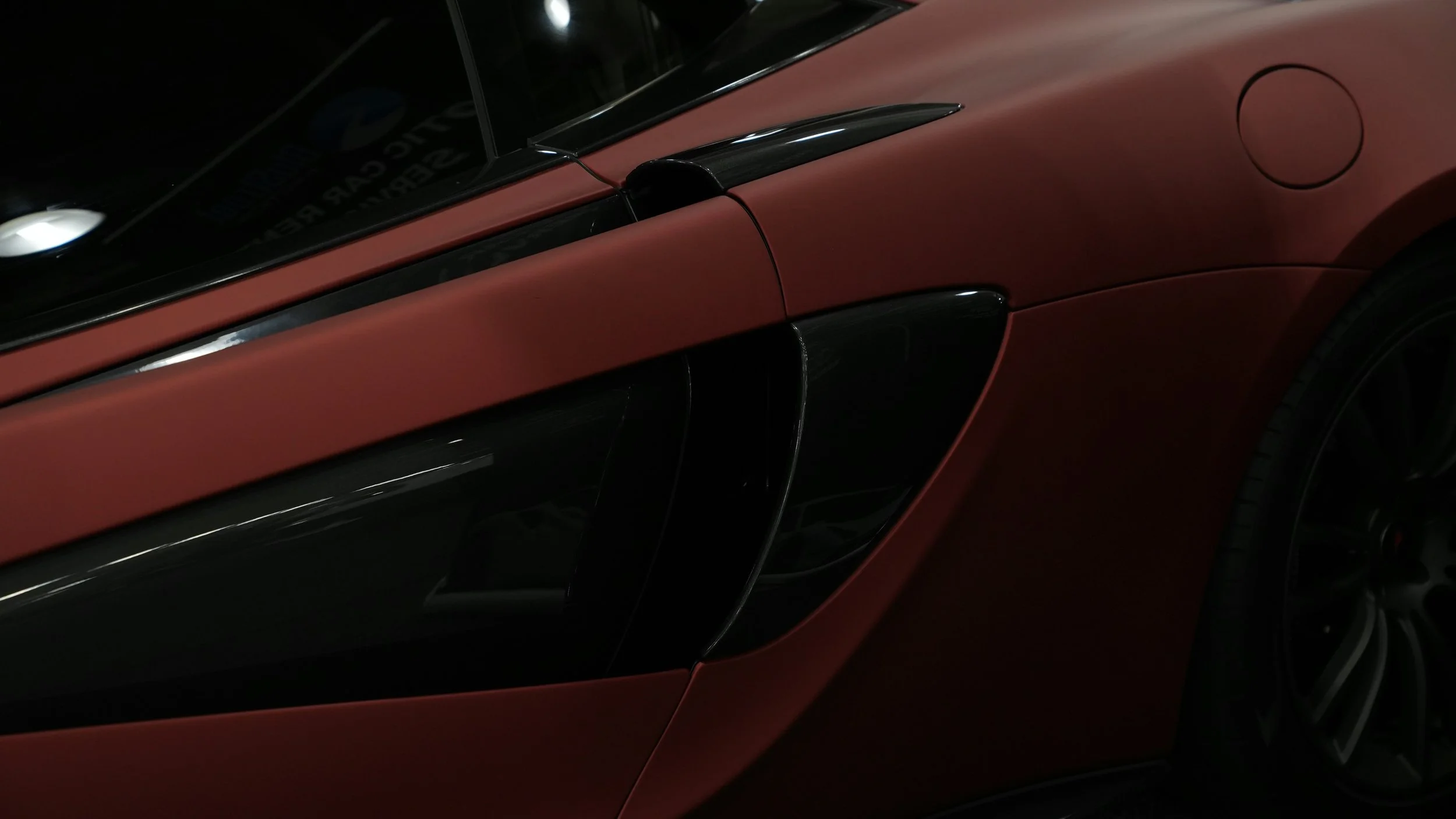 Close-up of a red sports car's side panel and wheel