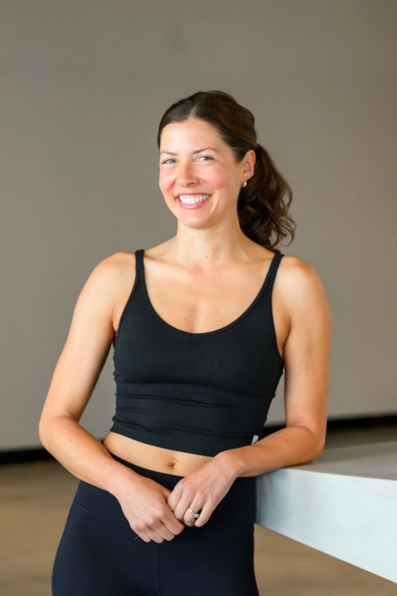 Woman in black athletic wear smiling indoors.