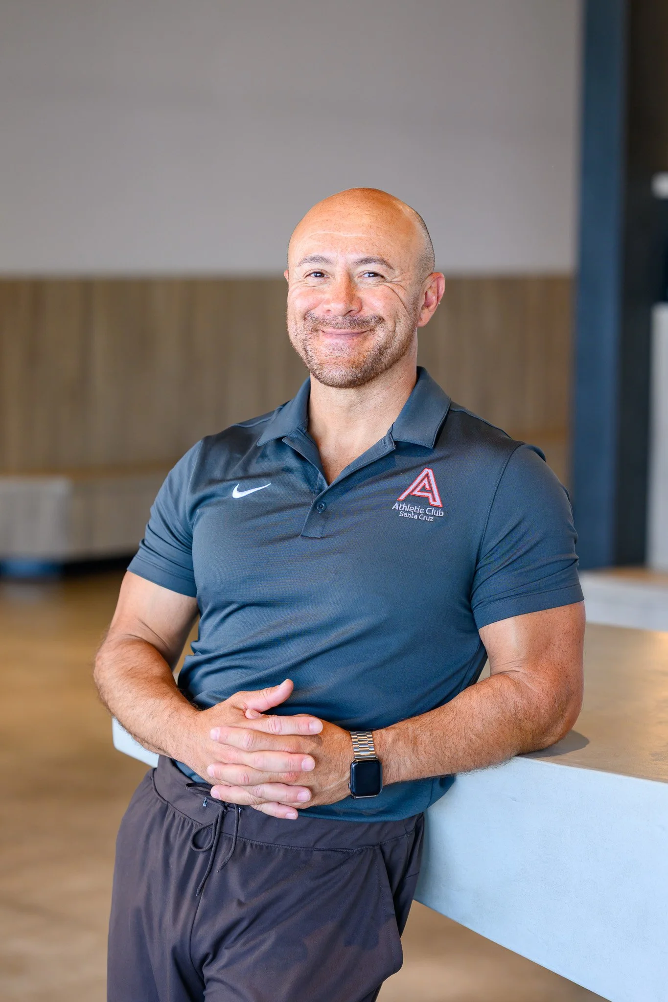 Woman in black outfit leaning on a counter, smiling, indoors.
