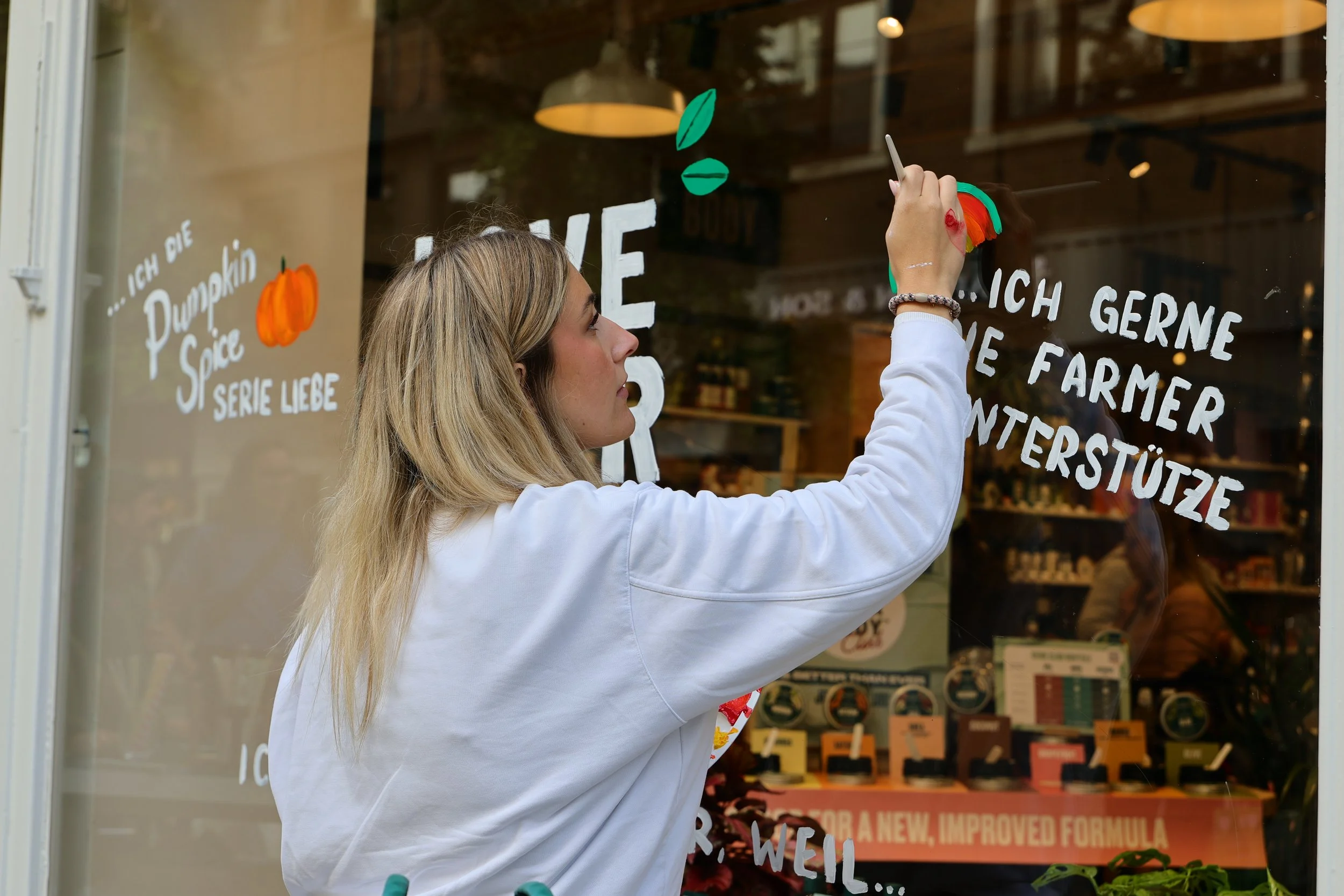 Illustratorin Svea Hansohn bemalt live das Schaufenster von The Body Shop in Düsseldorf mit dem Schriftzug Love Your Body