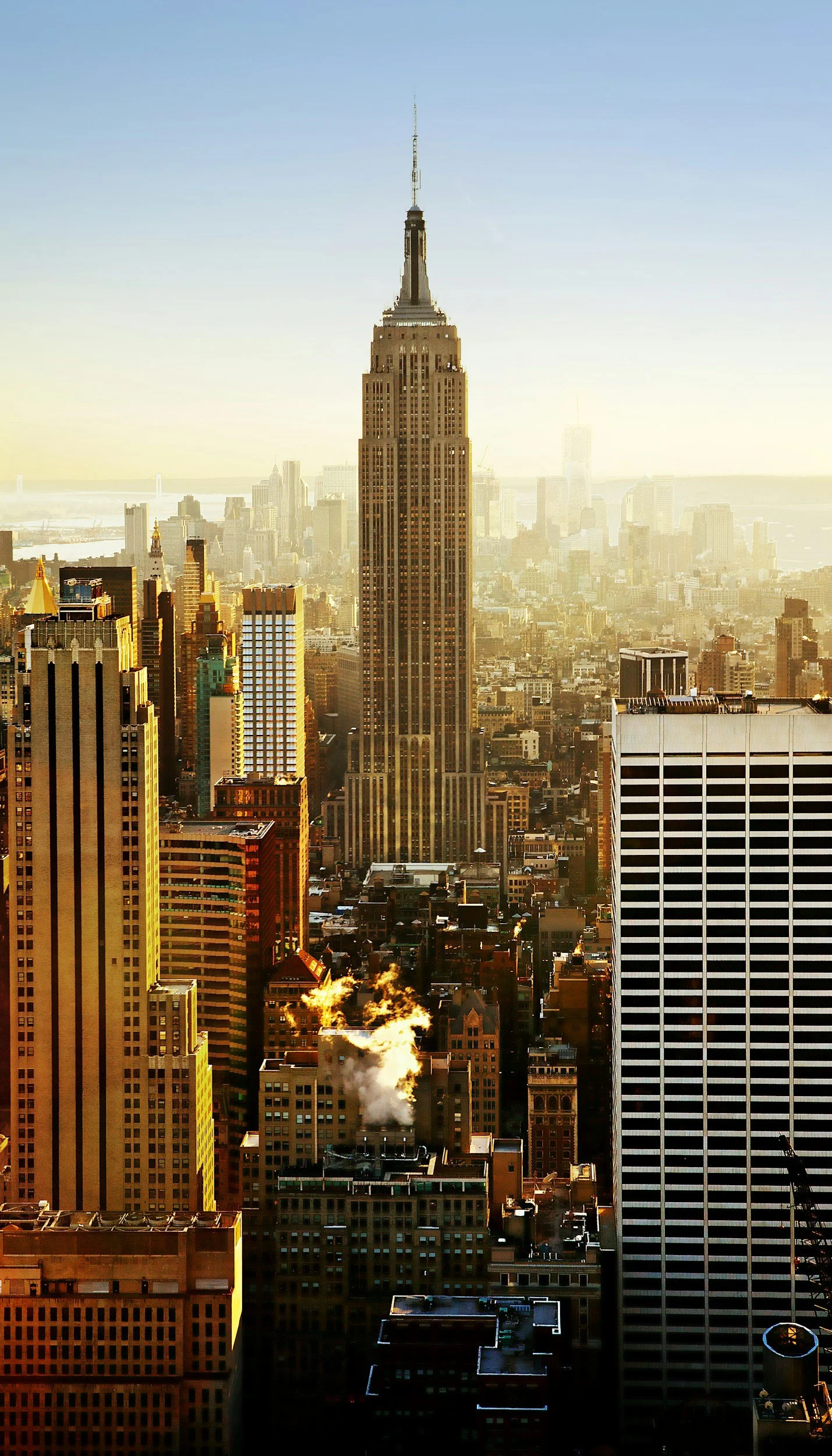 A cityscape of New York City featuring the Empire State Building with a hazy skyline in the background.