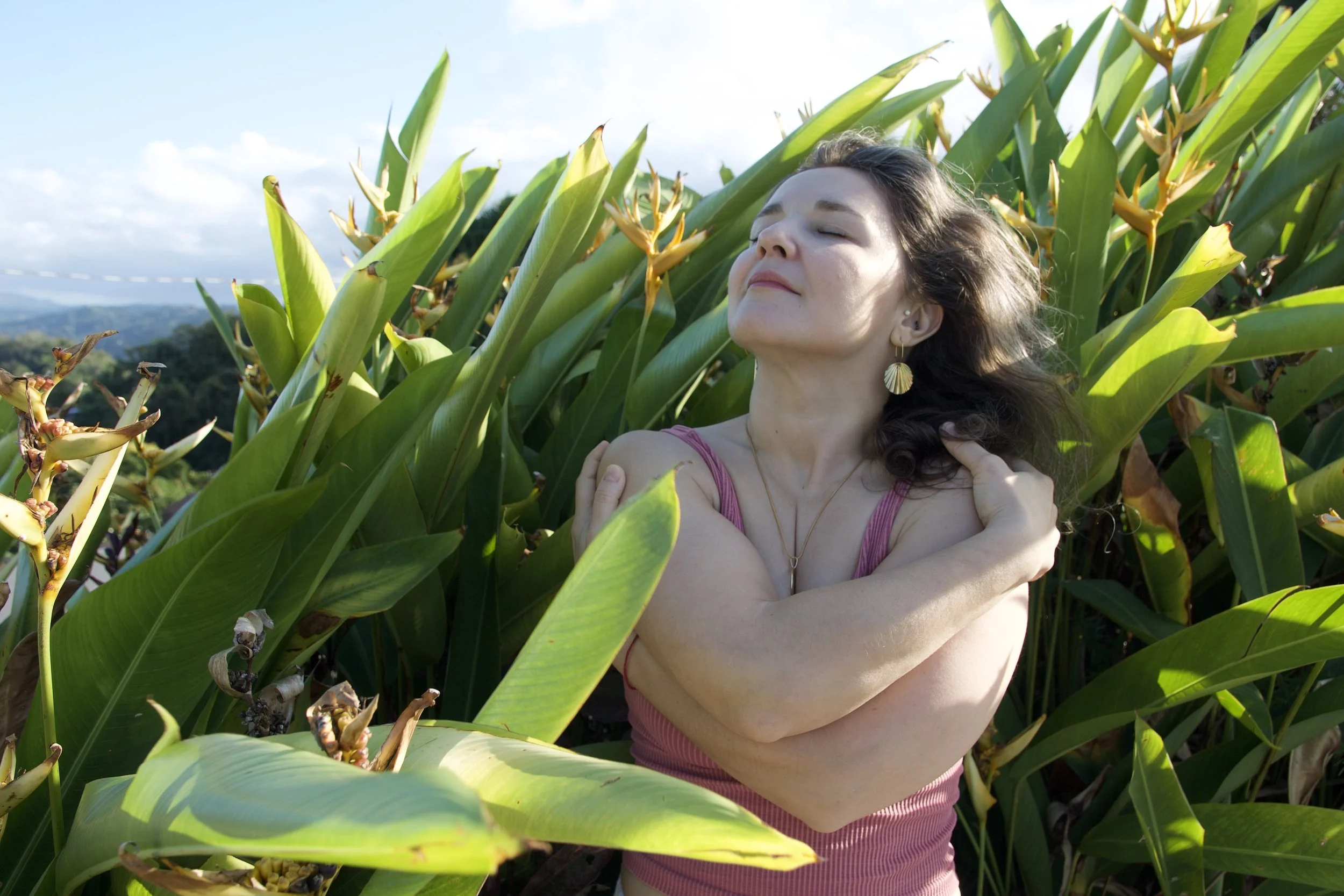 A woman practicing meditation outdoors at the Lincoln Memorial with white marble columns, light blue sky, and green trees in the background.