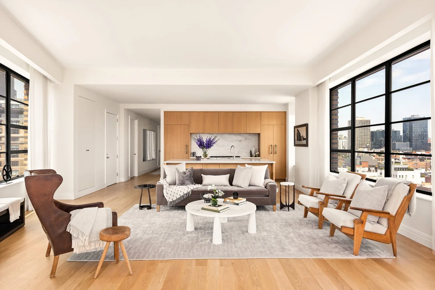 The living room staged to define scale, flow, and seating within the apartment’s signature curved window wall. Luxury condo living room staging at 10 Sullivan Place Residence 12A featuring curved windows and defined seating zones.