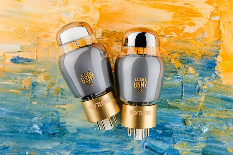 Overhead view of two Ray Tubes RESERVE 6SN7 vacuum tubes with metallic gray glass and orange lettering, set against an abstract oil painting.