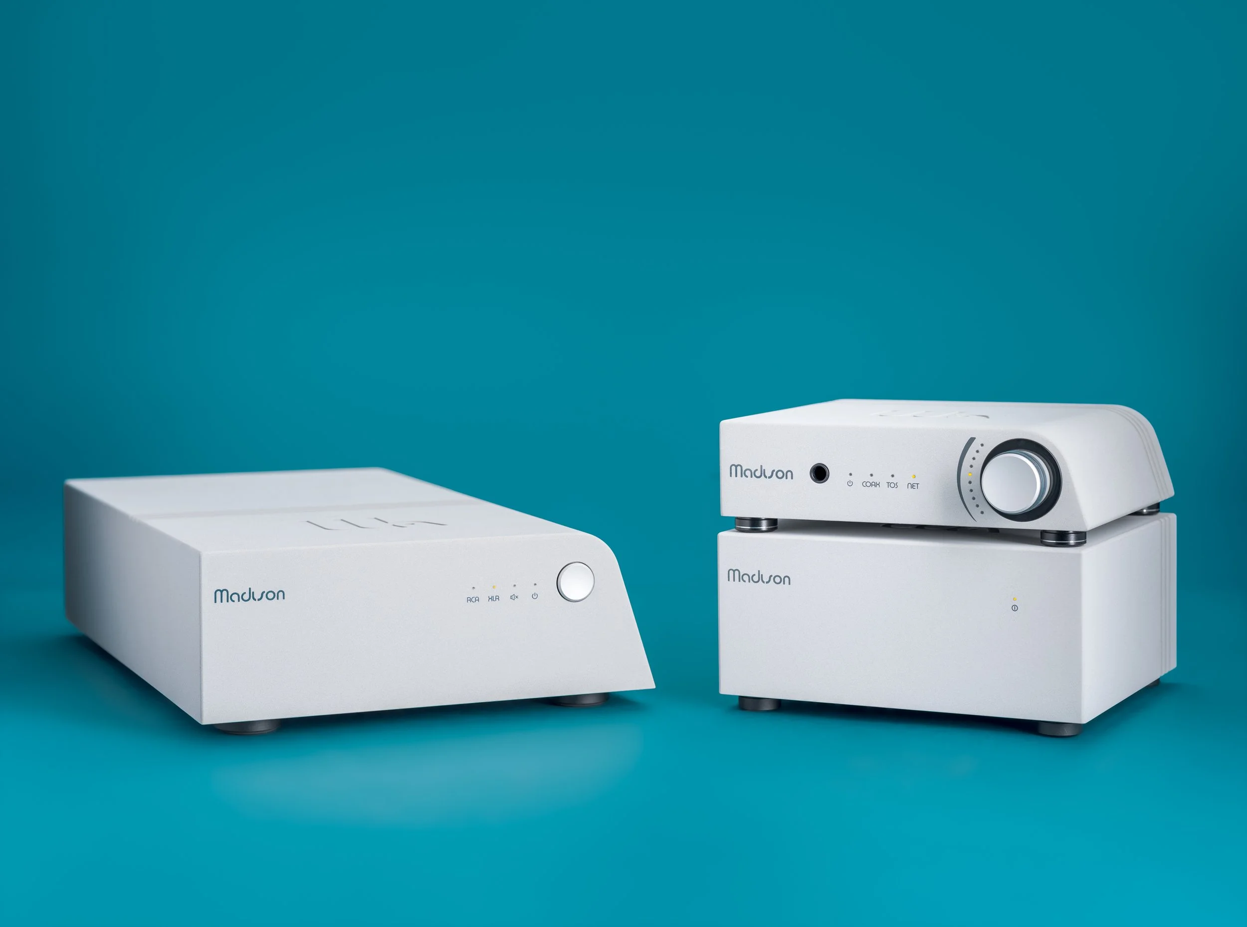 Front view of the Wattson Madison system against a teal background, with the Madison Amplifier on the left and the Madison Streamer and Madison Power S on the right, both angled in a three-quarter profile.