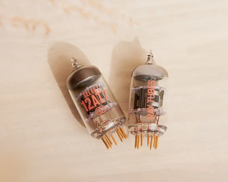 Overhead view of a pair of Ray Tubes SELECT 12AT7s laying on their sides against a light background.