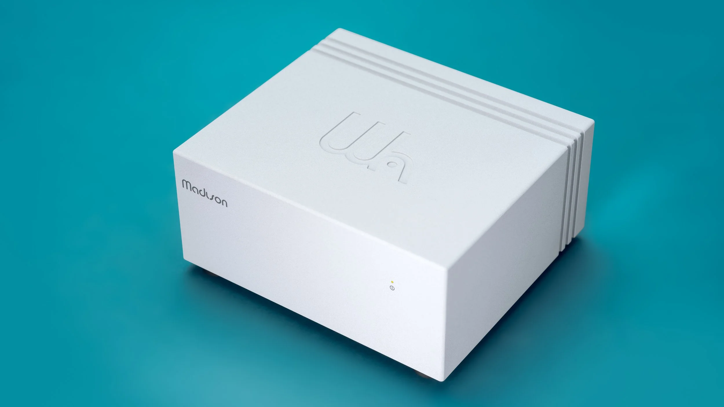 Light Gray Wattson Madison Power S shown in a down-oblique view against a teal background, highlighting its compact, milled-aluminum chassis.