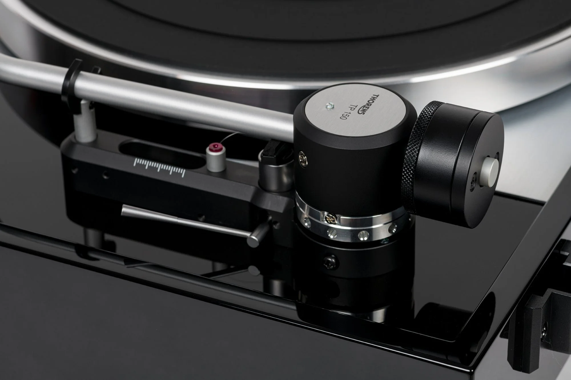 Close-up of the Thorens TD 1500 TP 150 tonearm assembly, showing the precision gimbal bearing housing, adjustable counterweight, anti-skate mechanism, and high-gloss black plinth.
