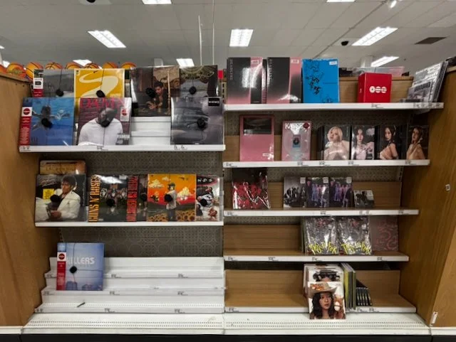 Small vinyl record display at Target featuring a mix of pop, indie, and catalog albums on a display rack.