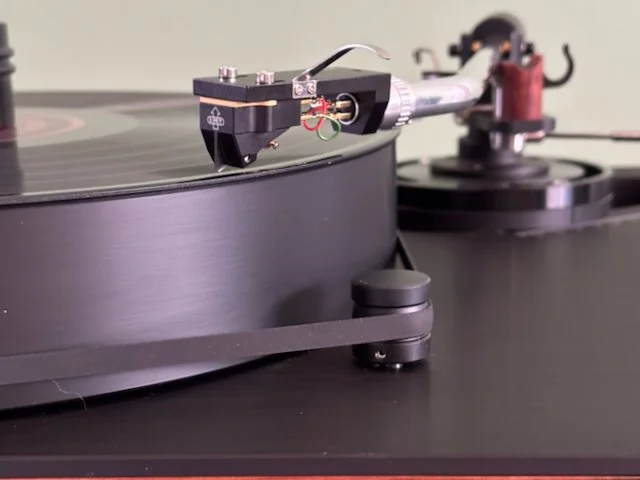 Close-up of Dr. Feickert Analogue Blackbird turntable in Black finish, showing Thomas Schick tonearm, EMT Pure Black moving coil cartridge in operation.