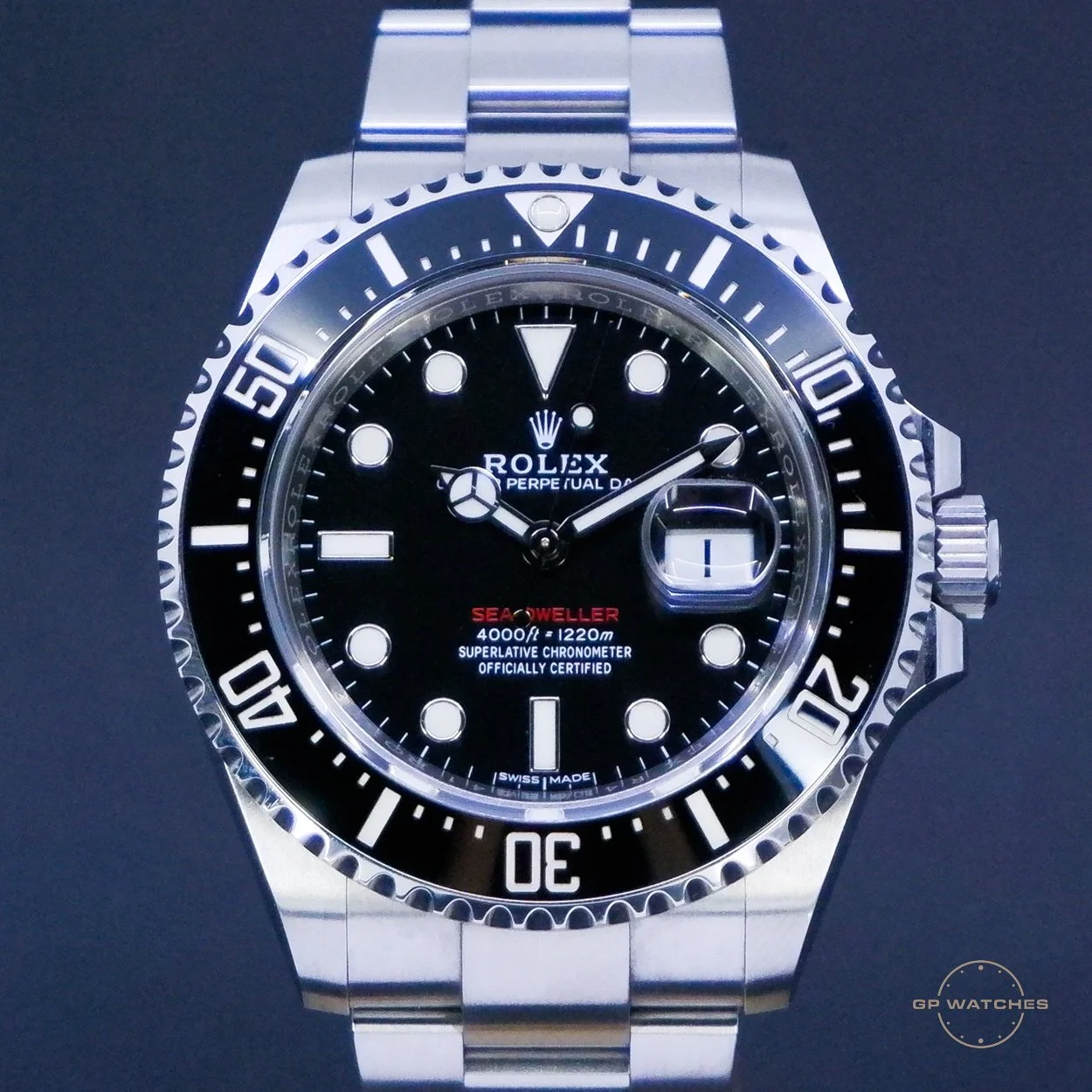 A close-up photograph of a Rolex Sea-Dweller Deepsea watch with a black dial, silver bezel, and stainless steel bracelet. The watch displays the date at 3 o'clock and has luminous hour markers with the red text 'Sea-Dweller' on the dial.