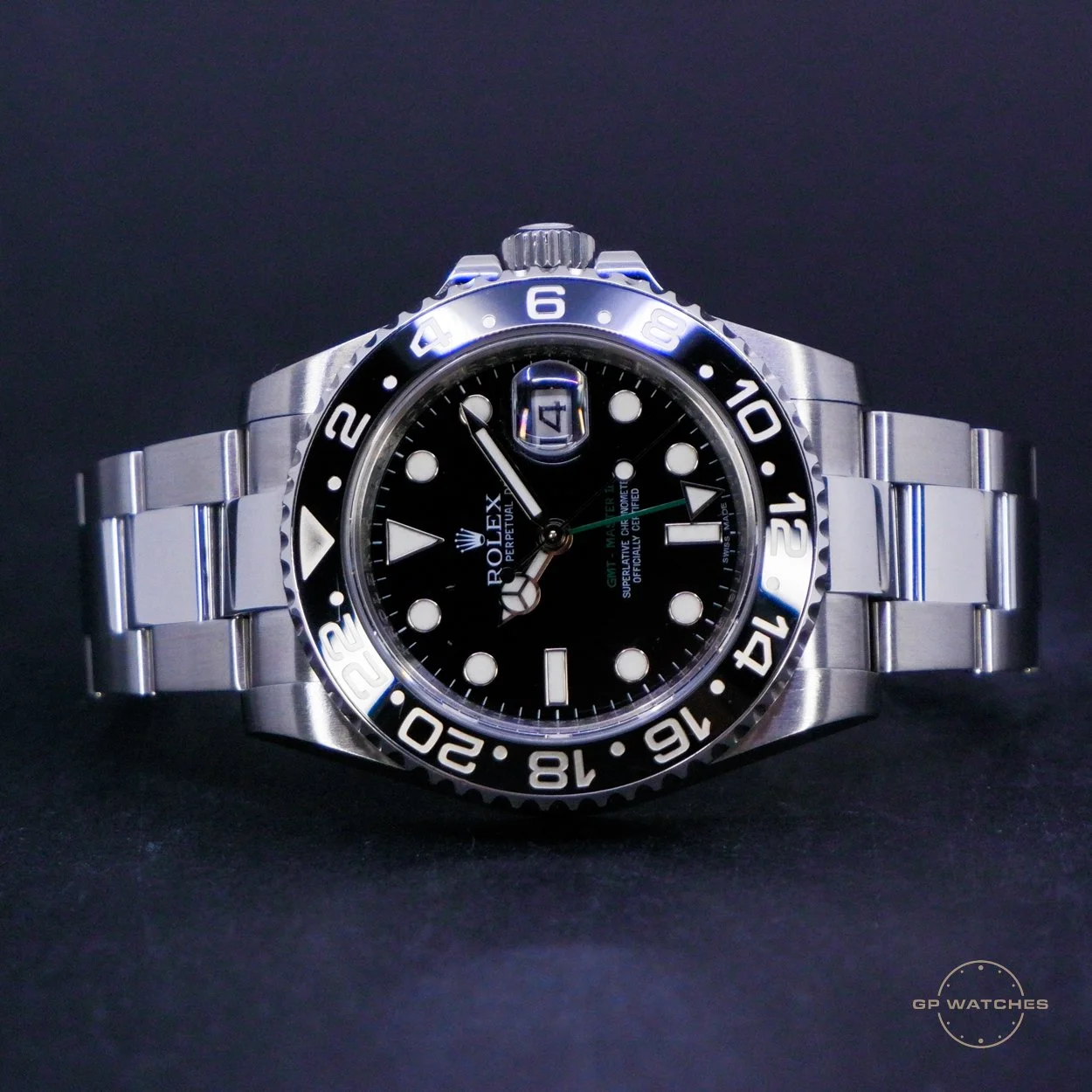 A Rolex black dial watch with a stainless steel band, luminescent markers, and a two-tone bezel featuring GMT and 12-hour markings.