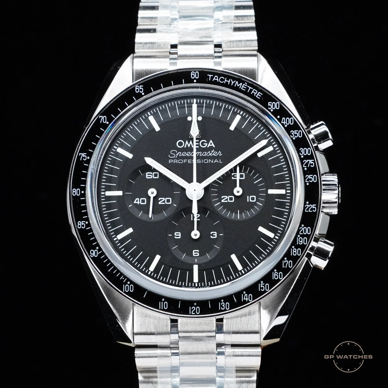 A silver stainless steel Omega Speedmaster Professional watch with a black dial, white markers, and chronograph subdials, set against a black background.