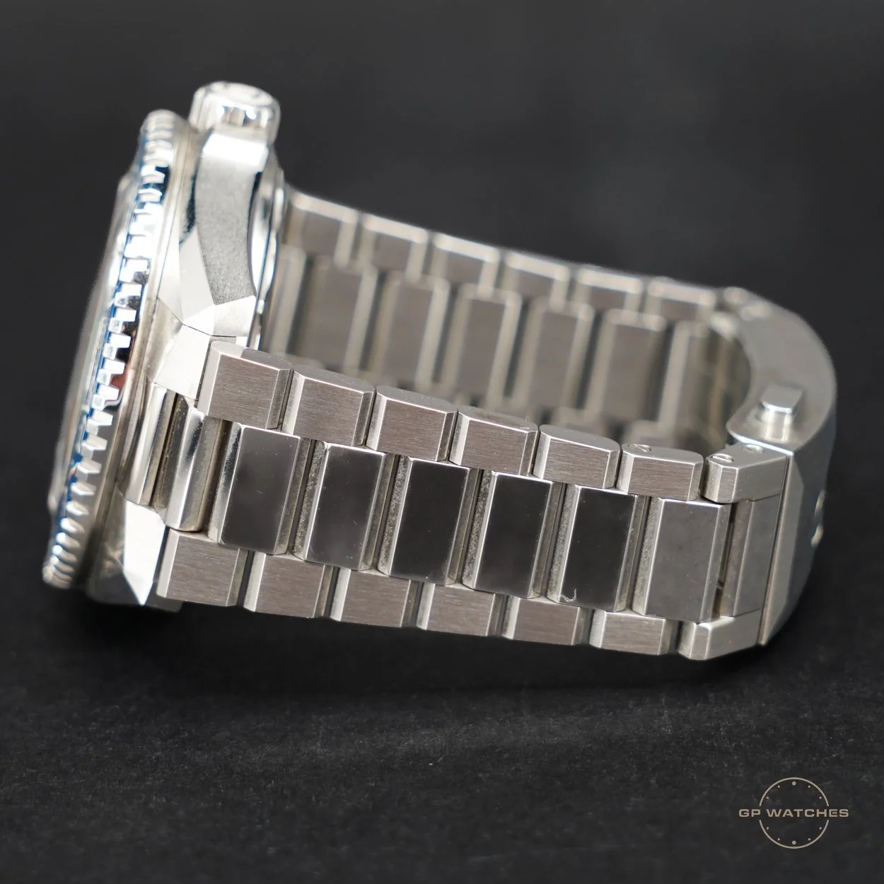 Close-up of a silver stainless steel watch with a metal link bracelet against a black background.