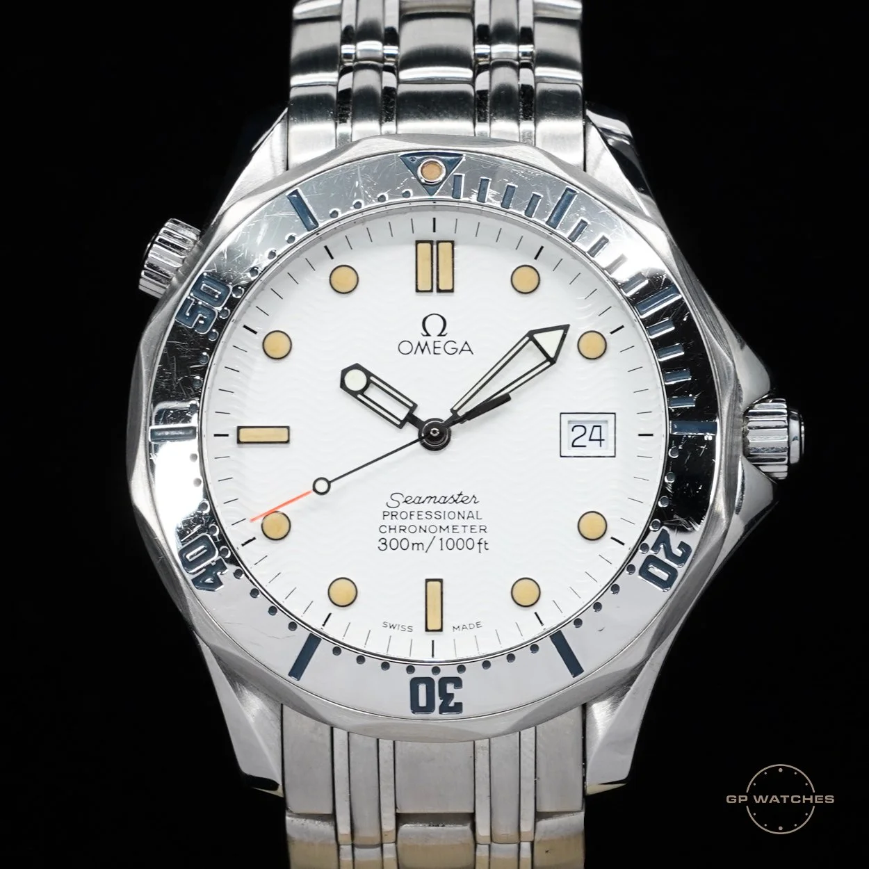 A silver Omega Seamaster professional dive watch with a white dial, black hour and minute hands, a black seconds hand with a red tip, a date window at 3 o'clock, and a rotating bezel with blue markings, set against a black background.