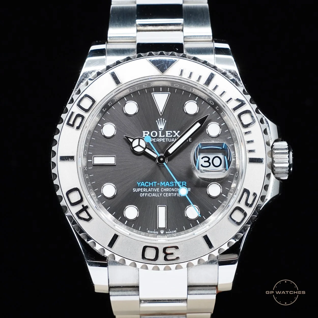 A Rolex Yacht-Master wristwatch with a black dial, silver bezel, and a date display at 3 o'clock. The watch has a stainless steel bracelet and luminous hour markers.