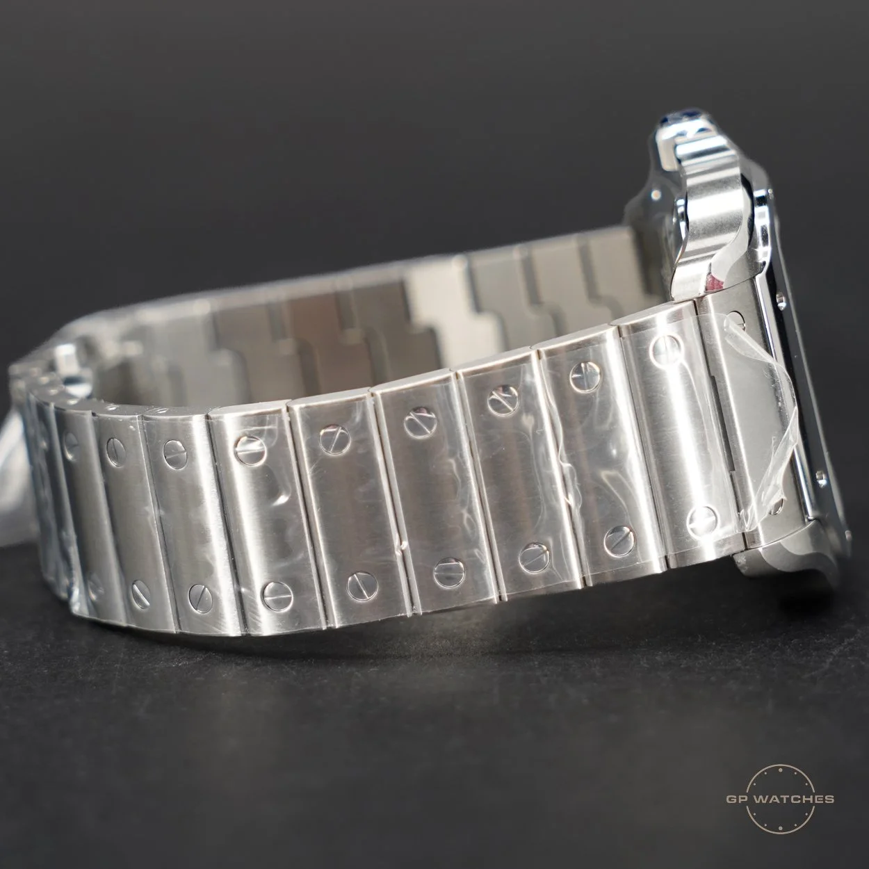 Close-up of a silver metal watch bracelet on a black background.