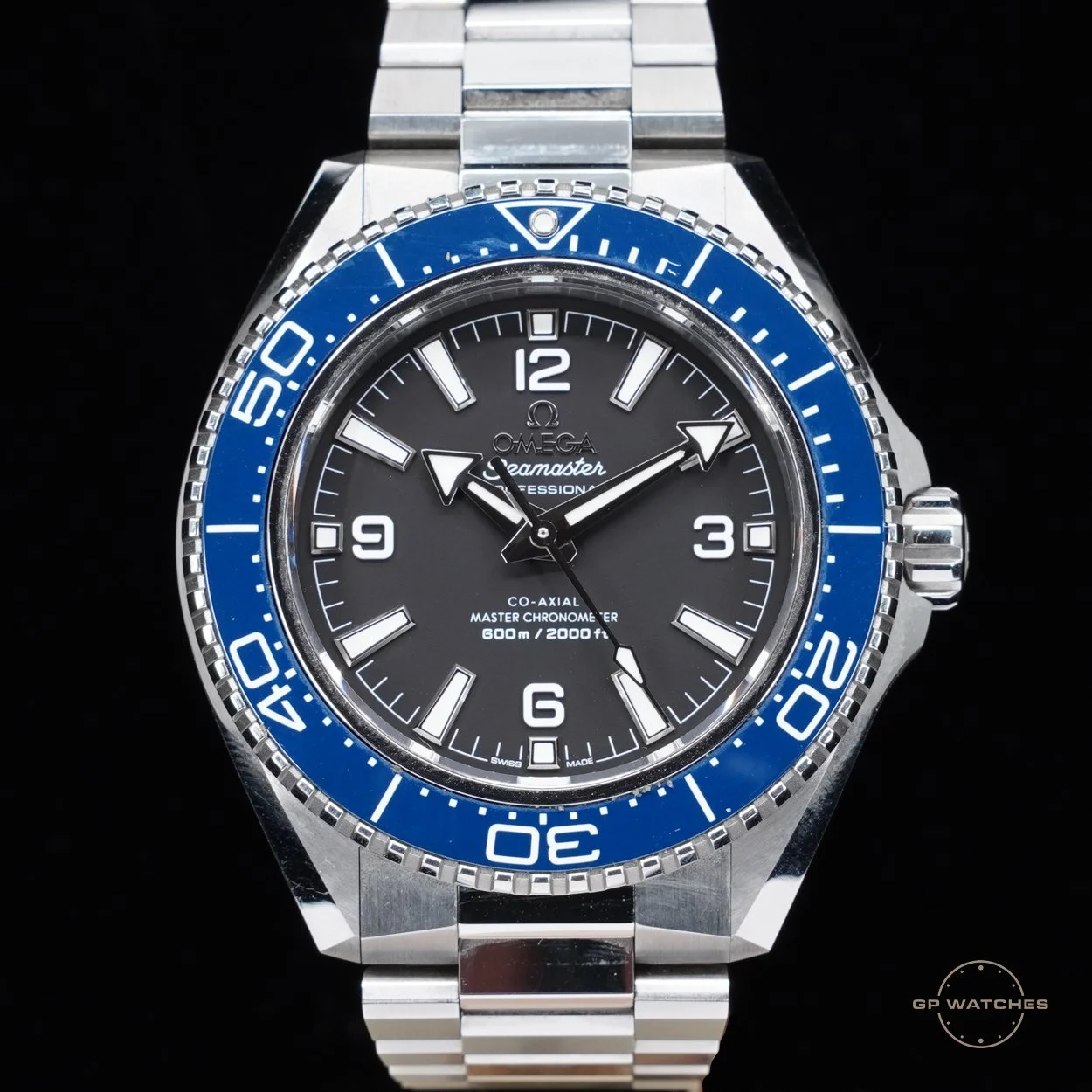 Close-up of an Omega Seamaster Professional wristwatch with a black dial, white markers, and a blue and silver unidirectional bezel, featuring the date window at 3 o'clock and a stainless steel bracelet.