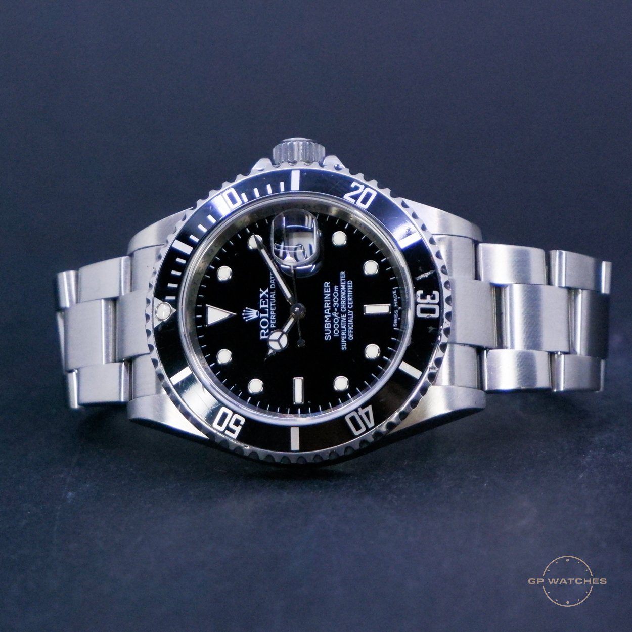 A Rolex Submariner watch with a stainless steel band, black dial, and a rotating bezel, displayed on a dark surface.
