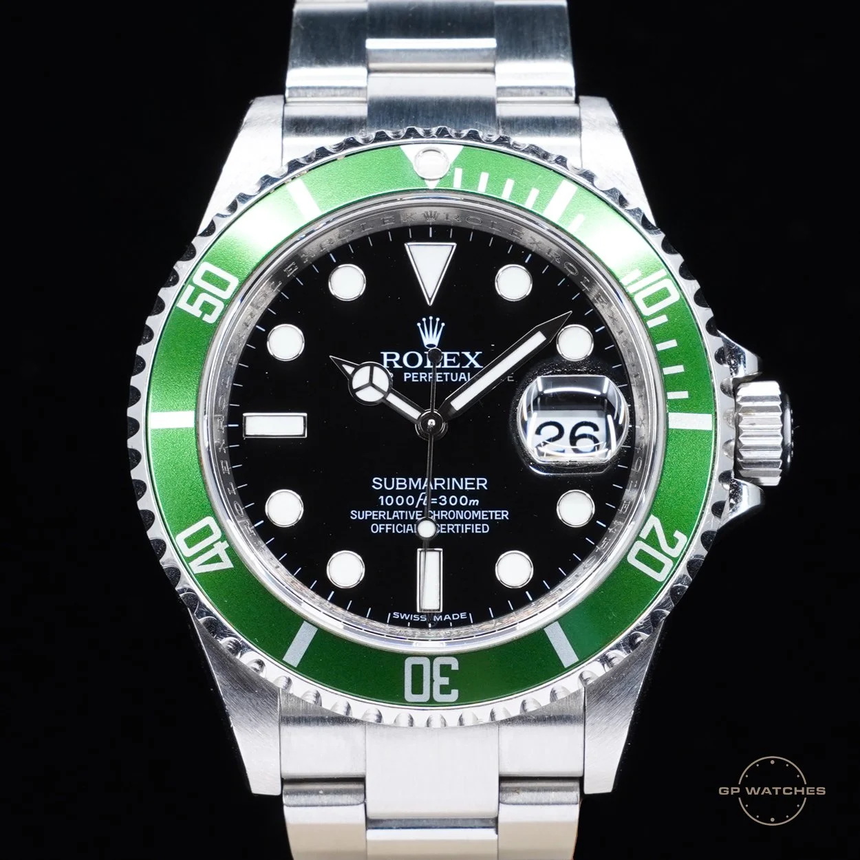 Close-up of a Rolex Submariner watch with a green bezel, black dial, and silver bracelet.
