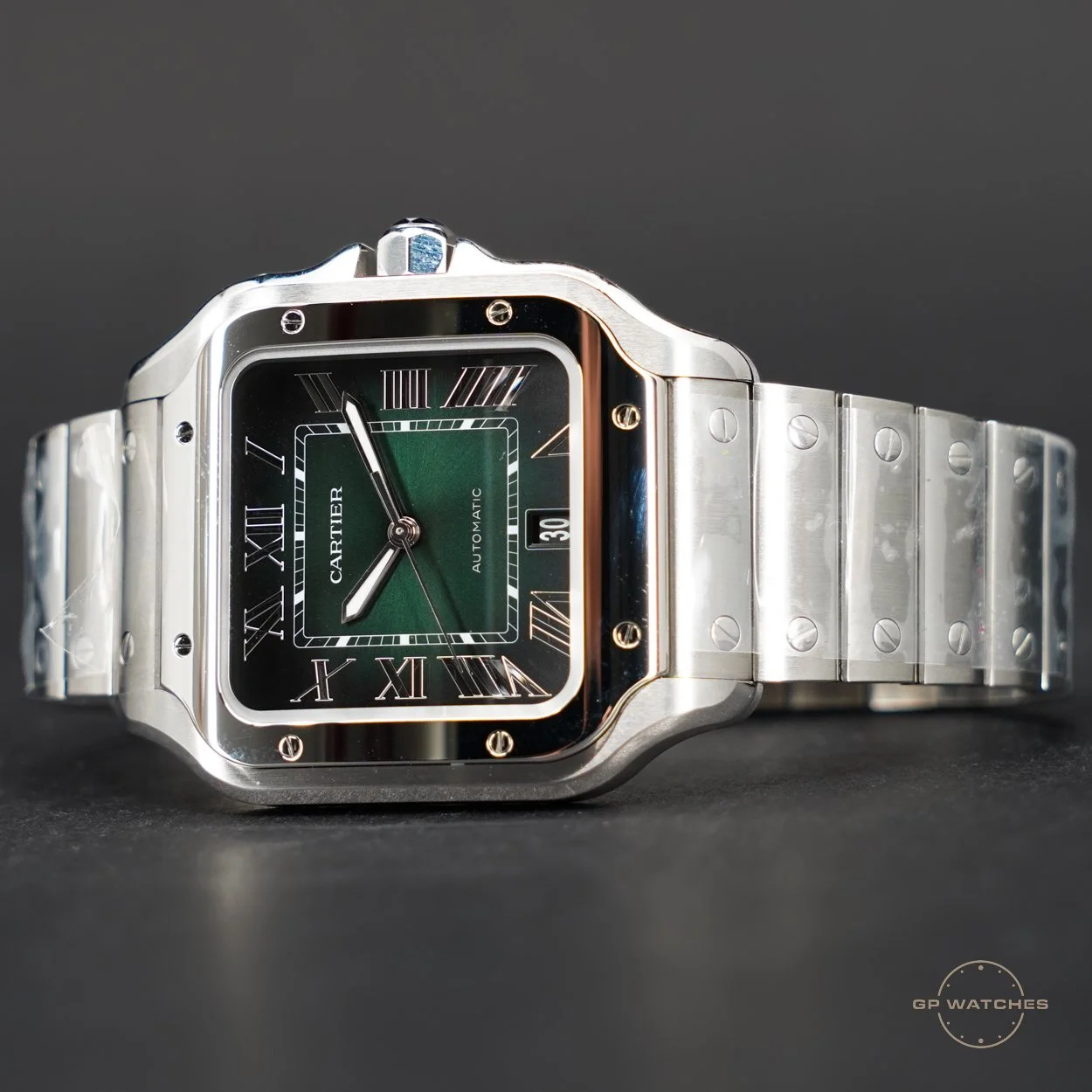 A luxury Cartier wristwatch with a square black face featuring Roman numerals, a green inner dial, and a date display, all set in a silver metal case and bracelet.