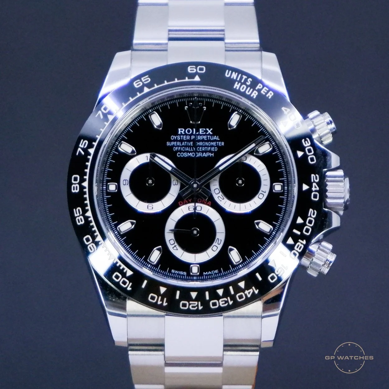 A Rolex Oyster Perpetual Cosmograph Daytona watch with a black and silver dial, three subdials, and a stainless steel band, displayed against a dark background.