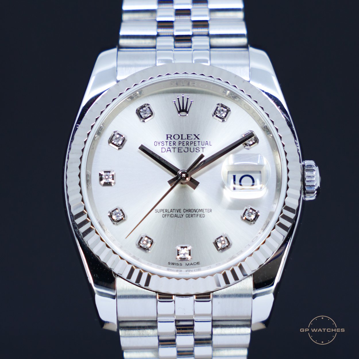 A close-up of a Rolex Oyster Perpetual Datejust watch with a silver dial, diamond hour markers, and a date display at 3 o'clock, set against a black background.
