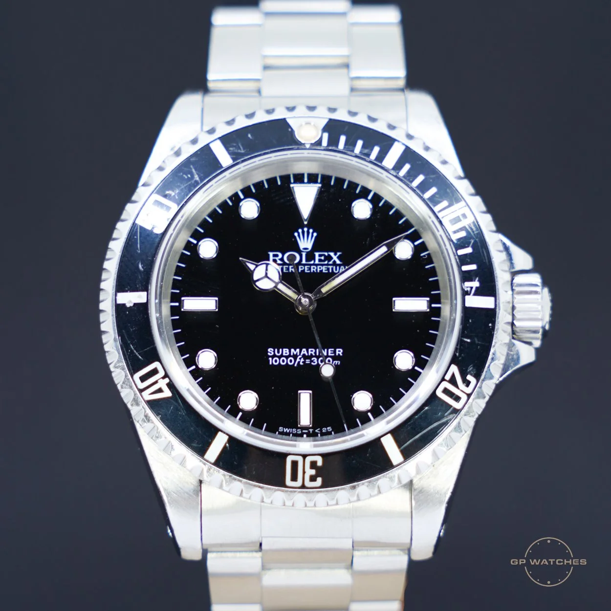 Close-up of a Rolex Submariner wristwatch with a black dial, silver bezel, and stainless steel bracelet.