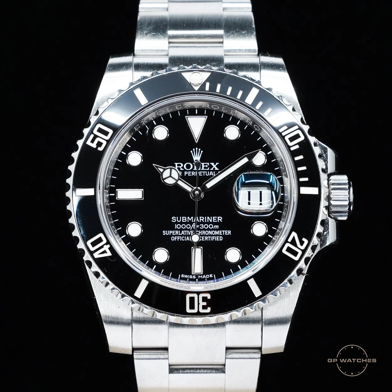A close-up of a Rolex Submariner wristwatch with a black dial, silver bezel, and stainless steel bracelet.