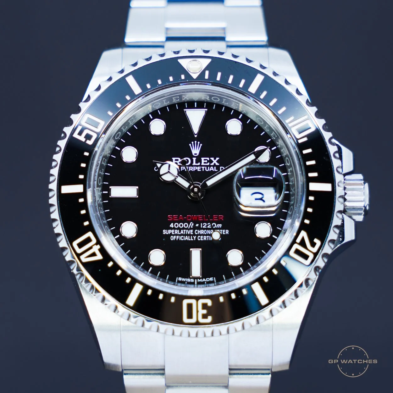 Close-up image of a Rolex Sea-Dweller watch with a black dial, silver bezel, and a date window showing the number 2.