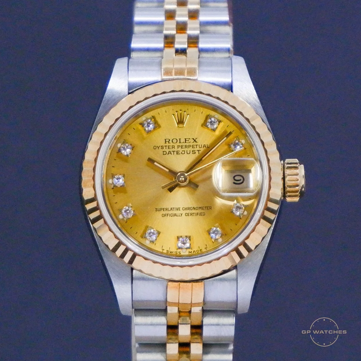 A Rolex Oyster Perpetual Datejust wristwatch with a gold dial, diamond hour markers, and a two-tone metal bracelet, featuring a date display at 3 o'clock.