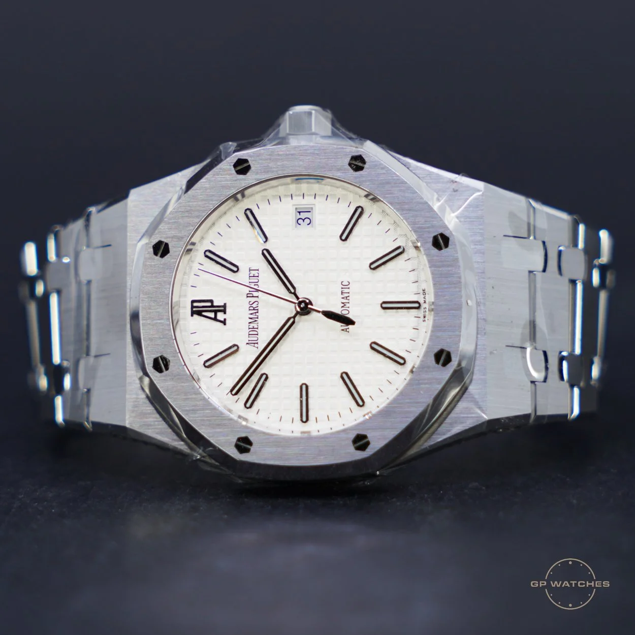 A silver Audemars Piguet wristwatch with a white face, black hour and minute hands, a red second hand, and a date display at the 3 o'clock position, set against a black background.