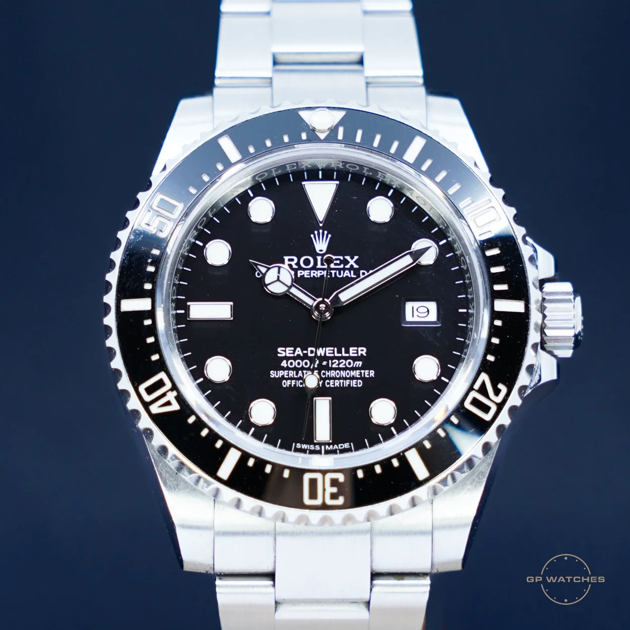 Close-up of a Rolex Sea-Dweller Deepsea watch with a black dial, silver bezel, and metal bracelet, displaying the time and date.