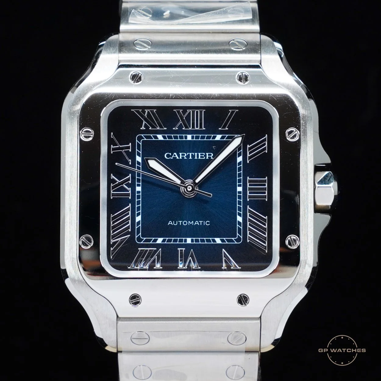 A luxury Cartier wristwatch with a square silver case, blue dial, Roman numeral hour markers, and steel bracelet.