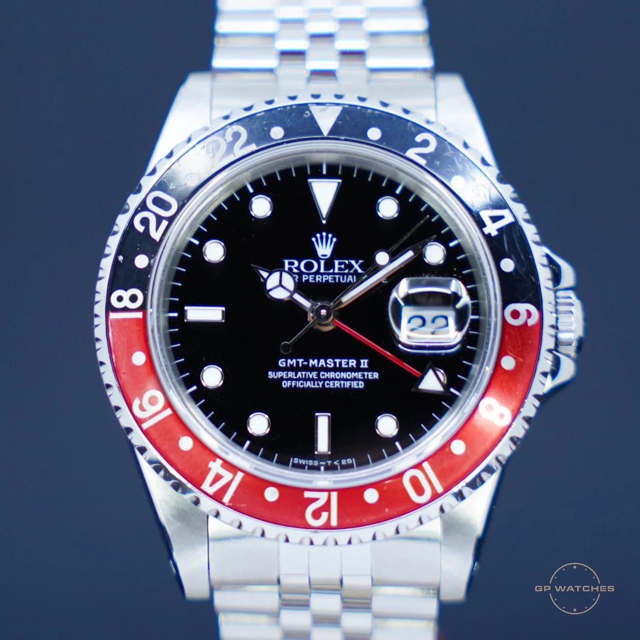 Close-up of a Rolex GMT-Master II watch with a black dial, silver bezel with red and blue sections, and a stainless steel bracelet.
