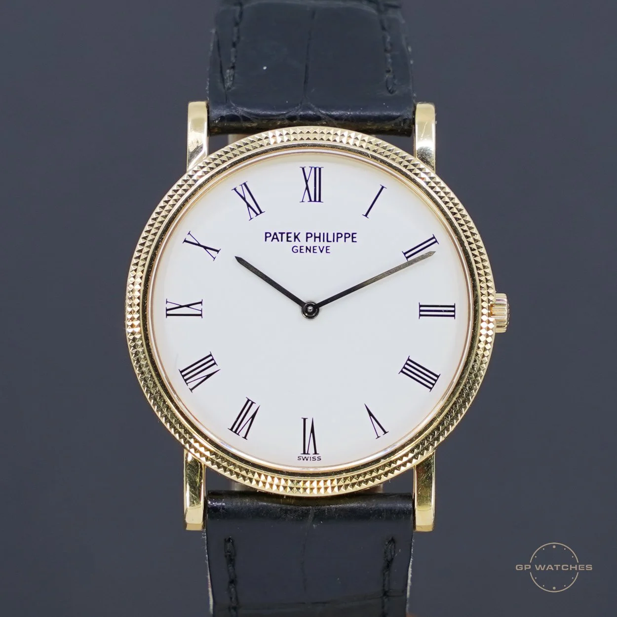 A luxury gold wristwatch with a white dial, black Roman numerals, and a black leather strap, displaying the time as 9:11.