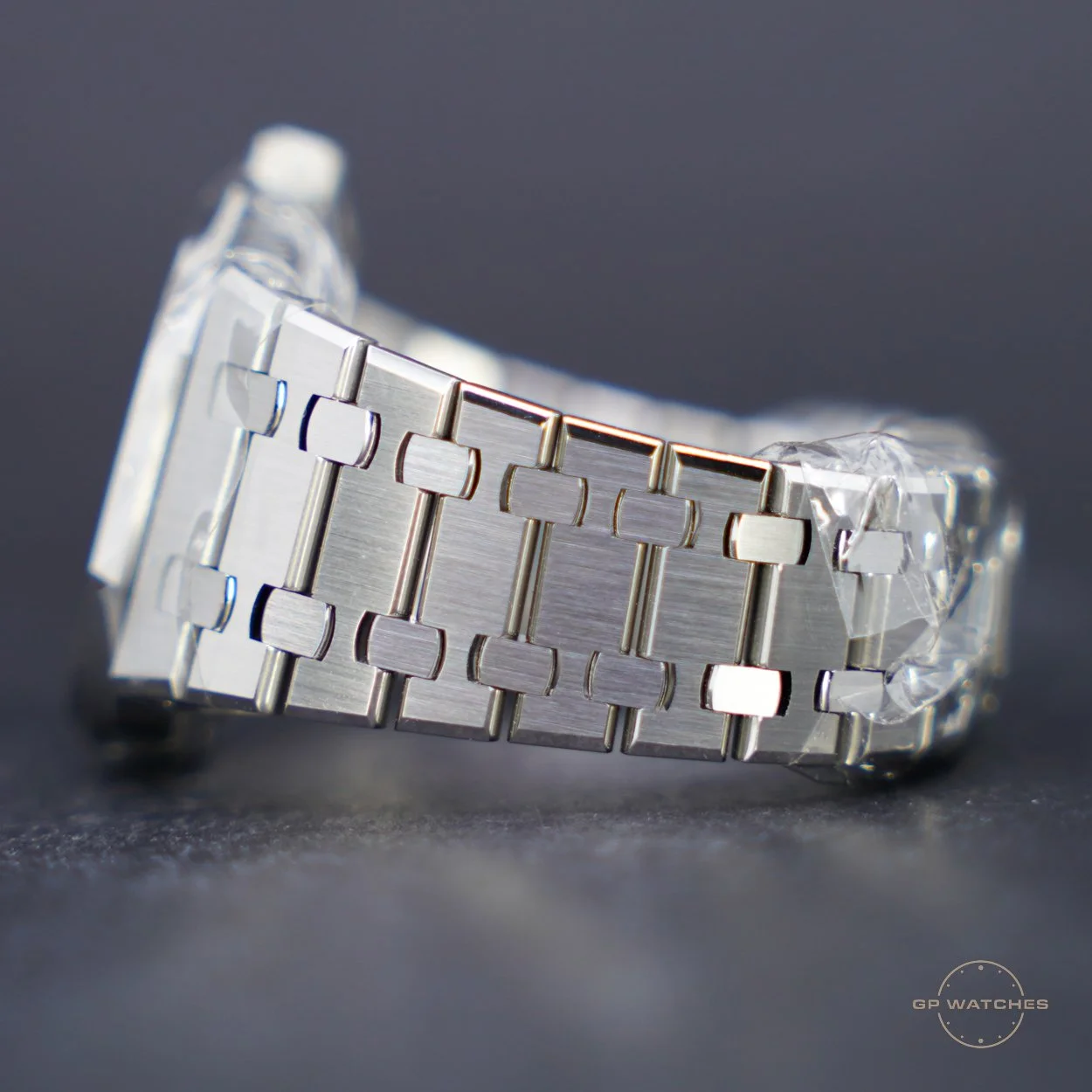 Close-up of a silver metal watch bracelet on a dark gray surface