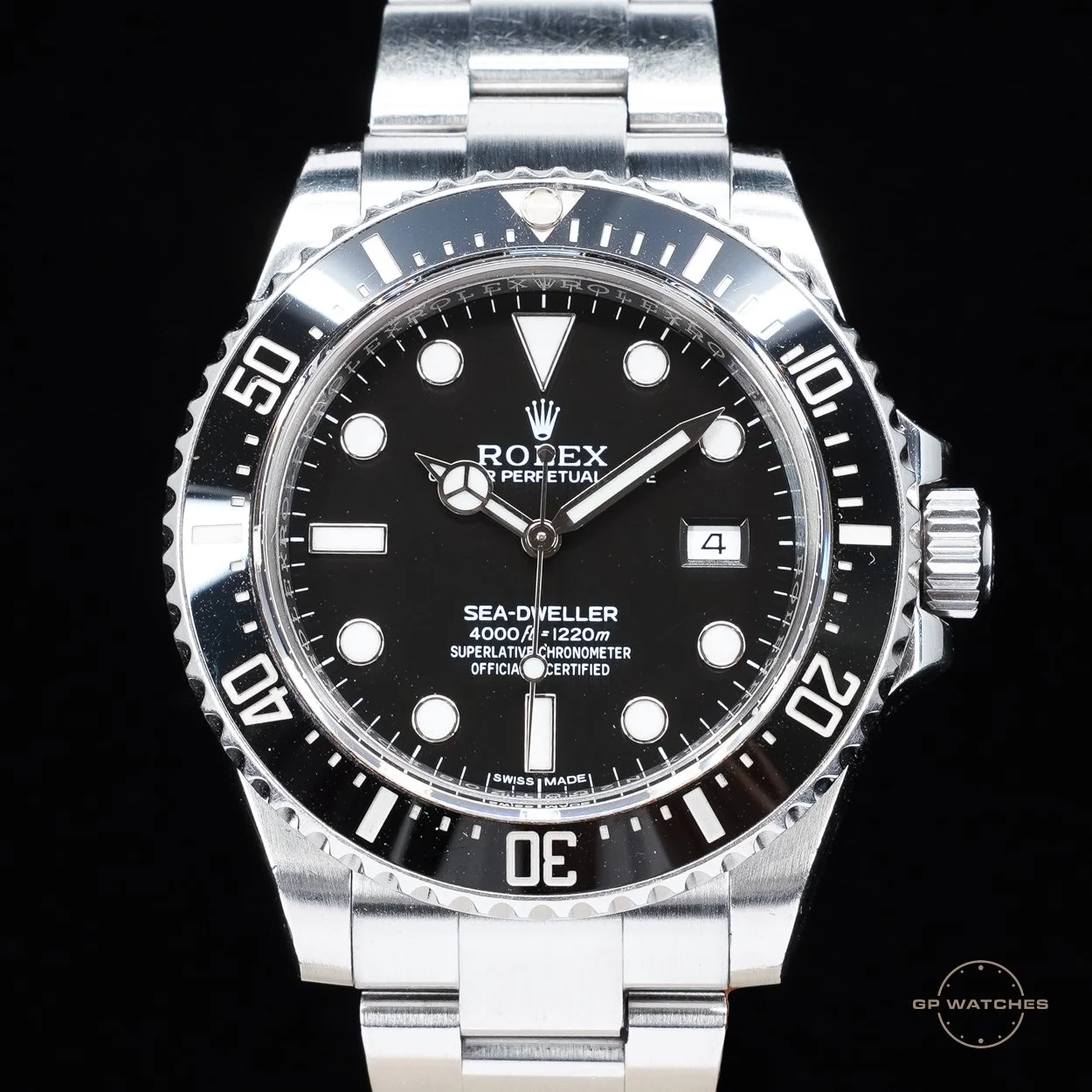 Close-up of a Rolex Sea-Dweller watch with a black dial, silver bezel, and stainless steel bracelet.