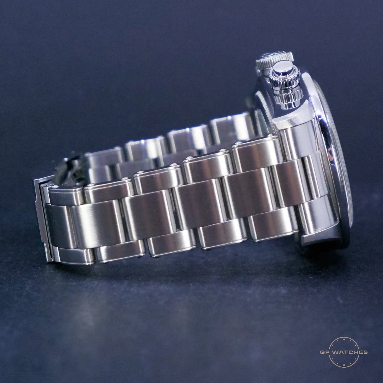 Side view of a stainless steel wristwatch with a metal link bracelet on a dark background.