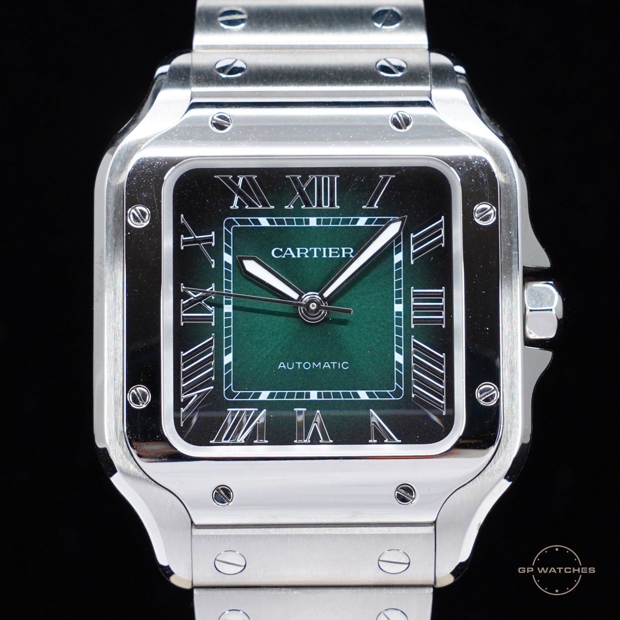 A luxury Cartier wristwatch with a square face, green dial, Roman numerals, and a stainless steel band.