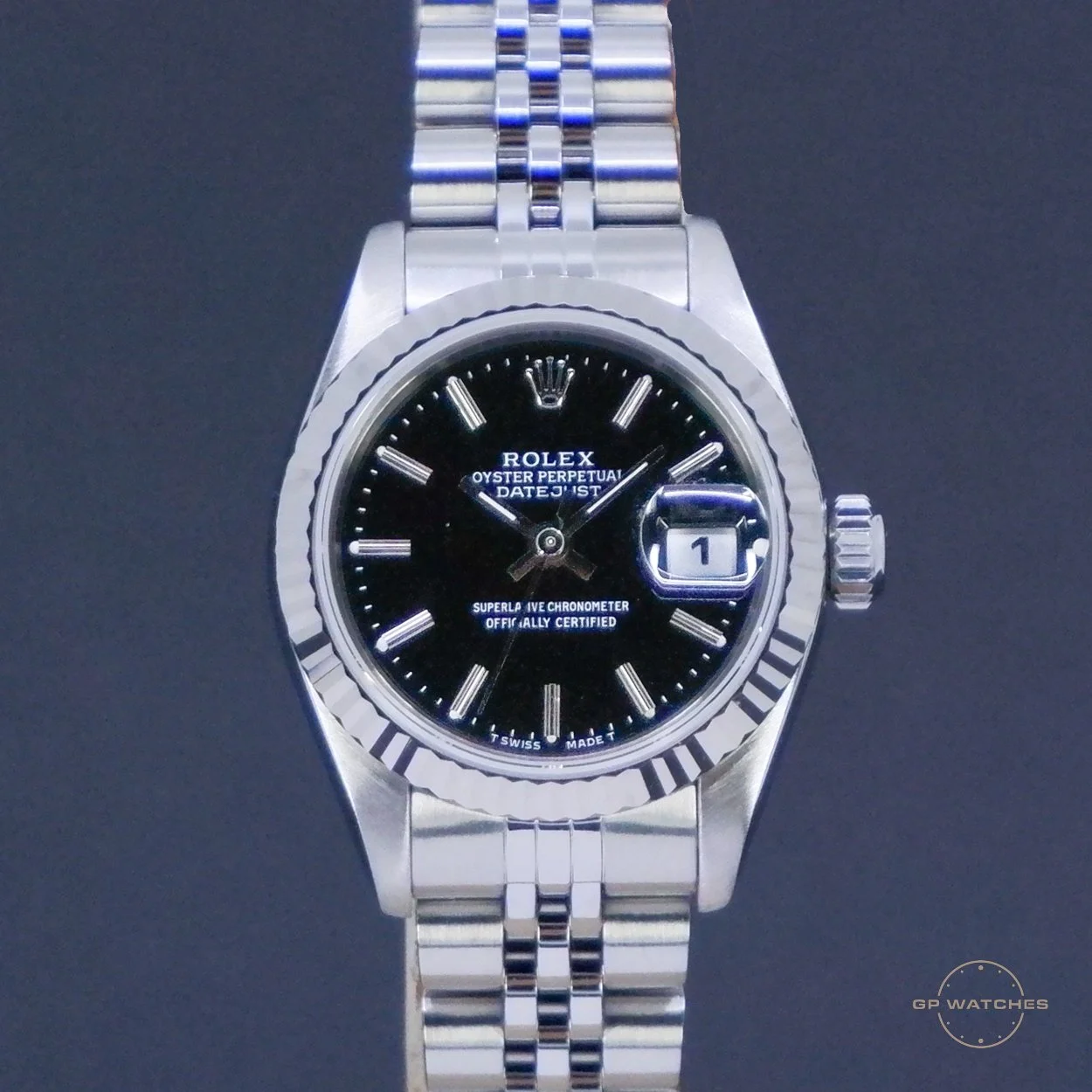 A silver Rolex Oyster Perpetual Datejust wristwatch with a black dial, Roman numeral hour markers, a date display at 3 o'clock, and a Jubilee bracelet.