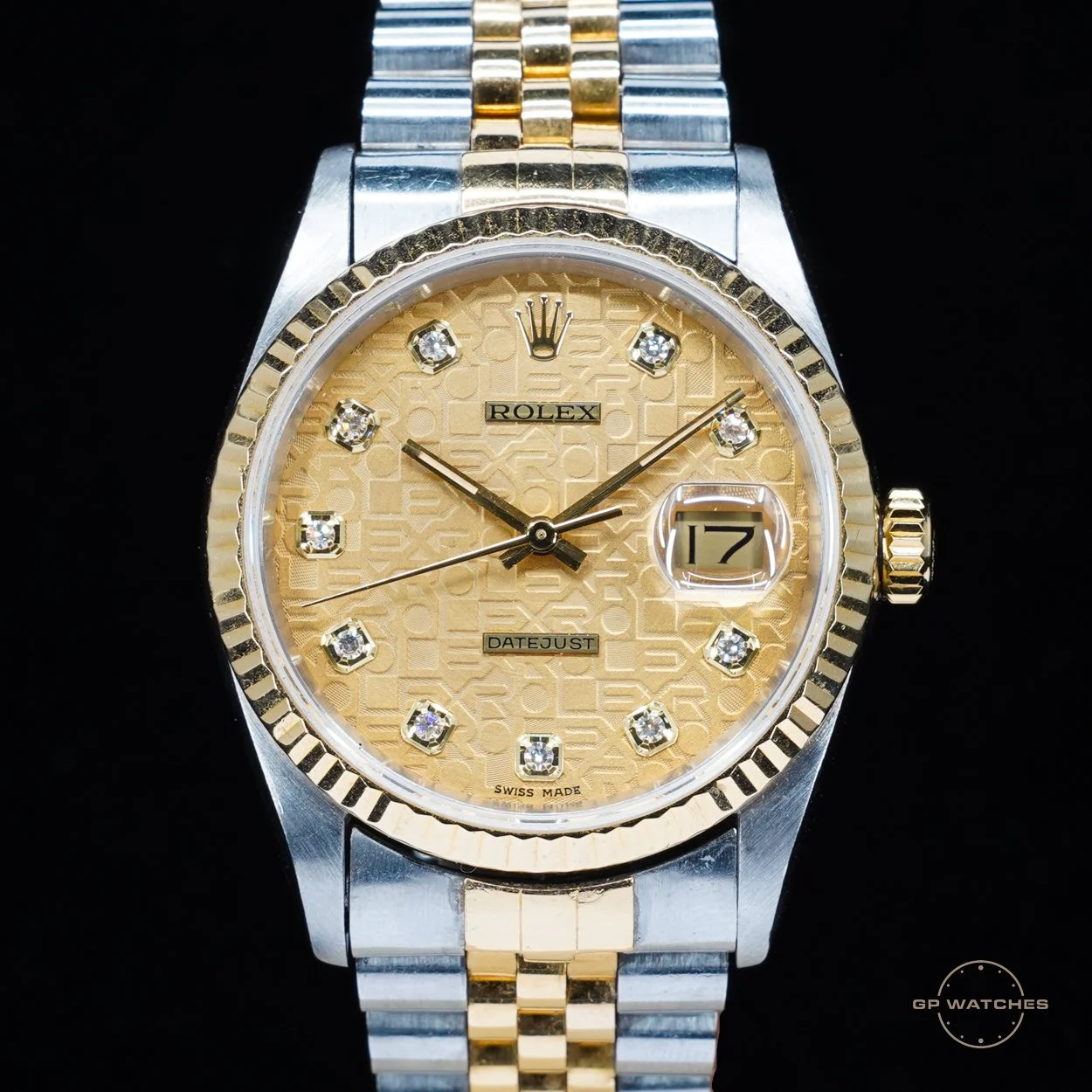 A Rolex wristwatch with a two-tone metal band, gold and silver, featuring a gold dial with diamond hour markers, a date window at 3 o'clock, and a fluted gold bezel.