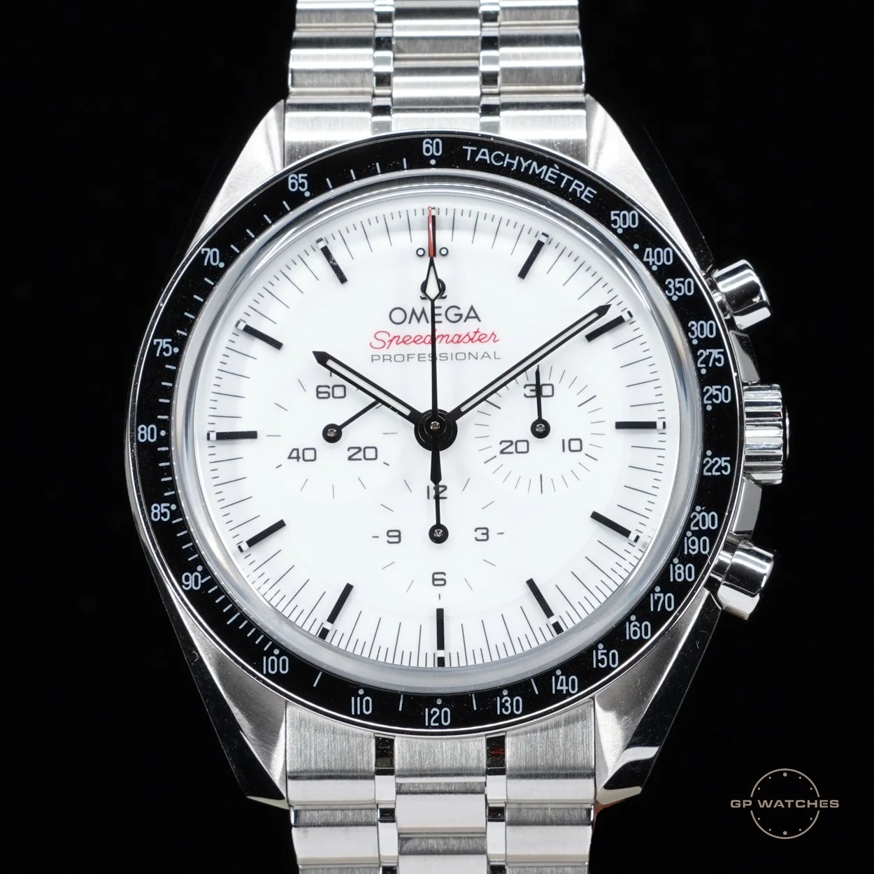 A close-up of a stainless steel Omega Speedmaster Professional watch with a white dial, black tachymeter bezel, and three subdials, showing the time and chronograph functions.