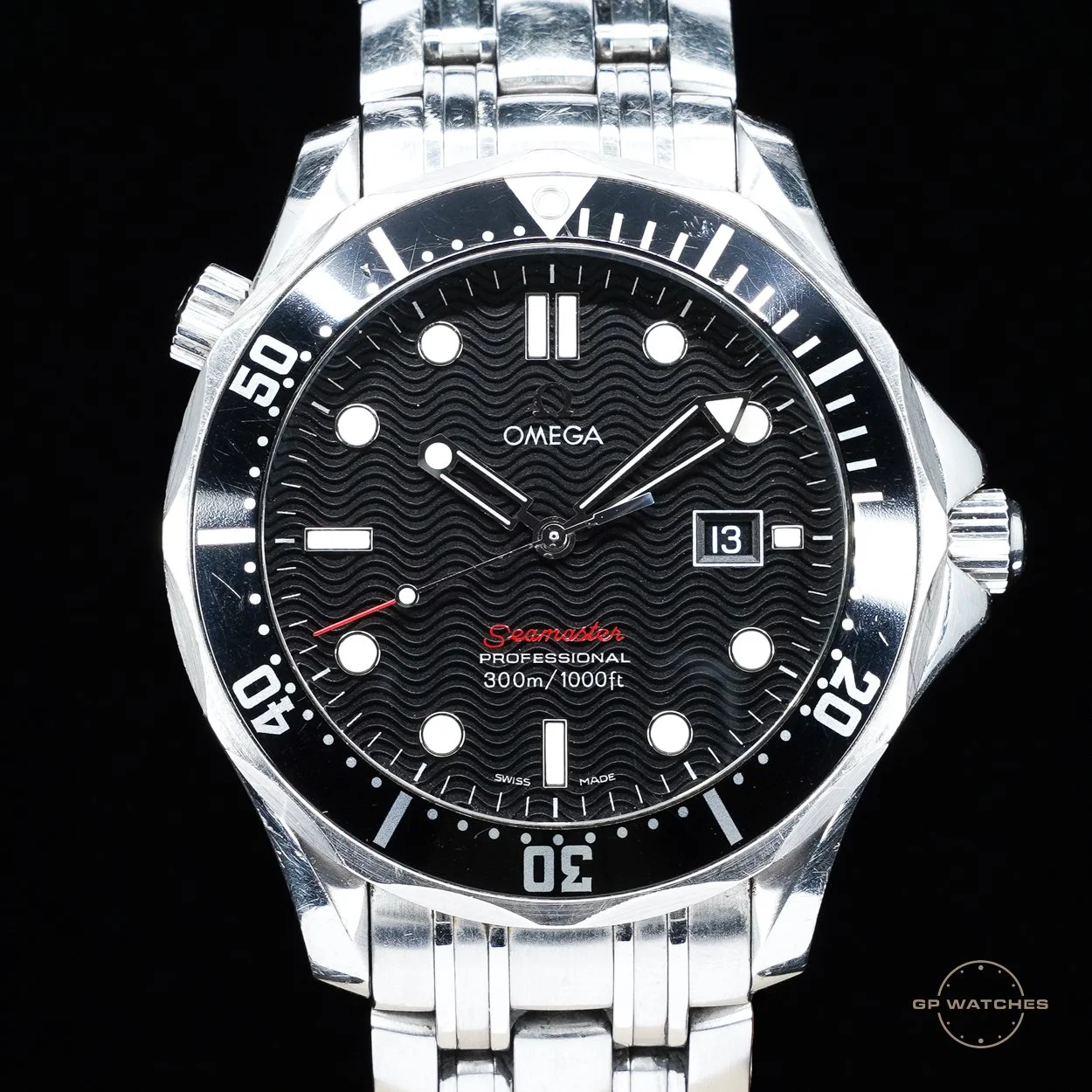 A stainless steel Omega Seamaster Professional watch with a black wave-pattern dial, white markers, and a date window at 3 o'clock, against a black background.