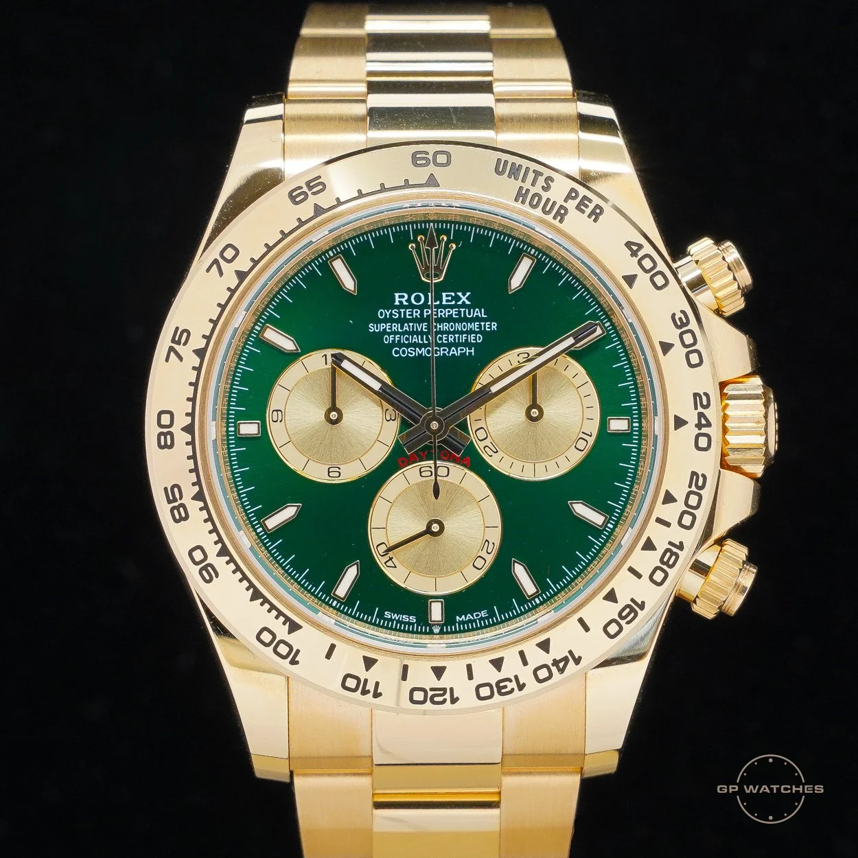A gold Rolex Cosmograph Daytona watch with a green dial and gold subdials, featuring a tachymeter bezel and three pushers on the side.