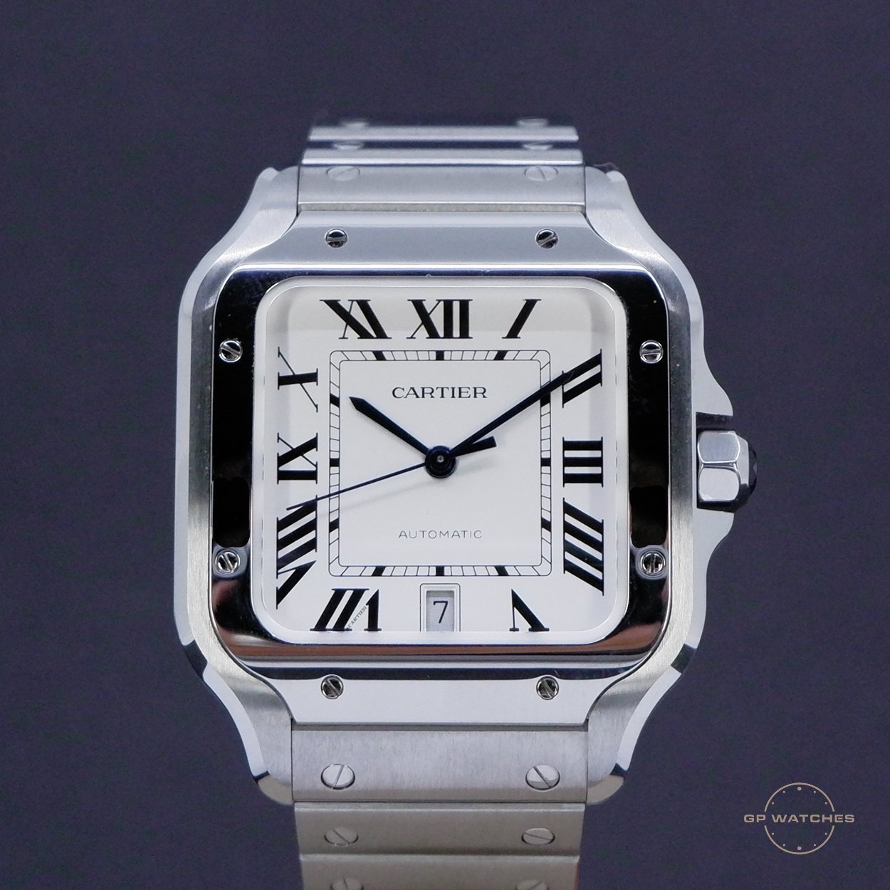 A Cartier watch with a square, silver-tone case and bracelet, white dial, black Roman numeral hour markers, and blue sword-shaped hands. The watch has a date window at 6 o'clock and a small seconds subdial.
