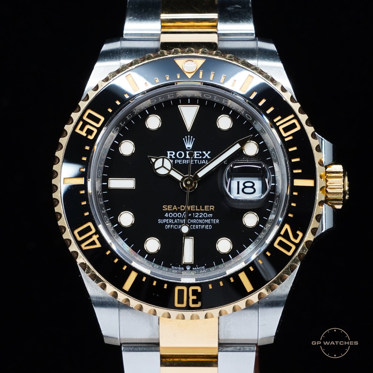 A two-tone Rolex Sea-Dweller watch with a black dial, date display, and a black and gold rotating bezel.