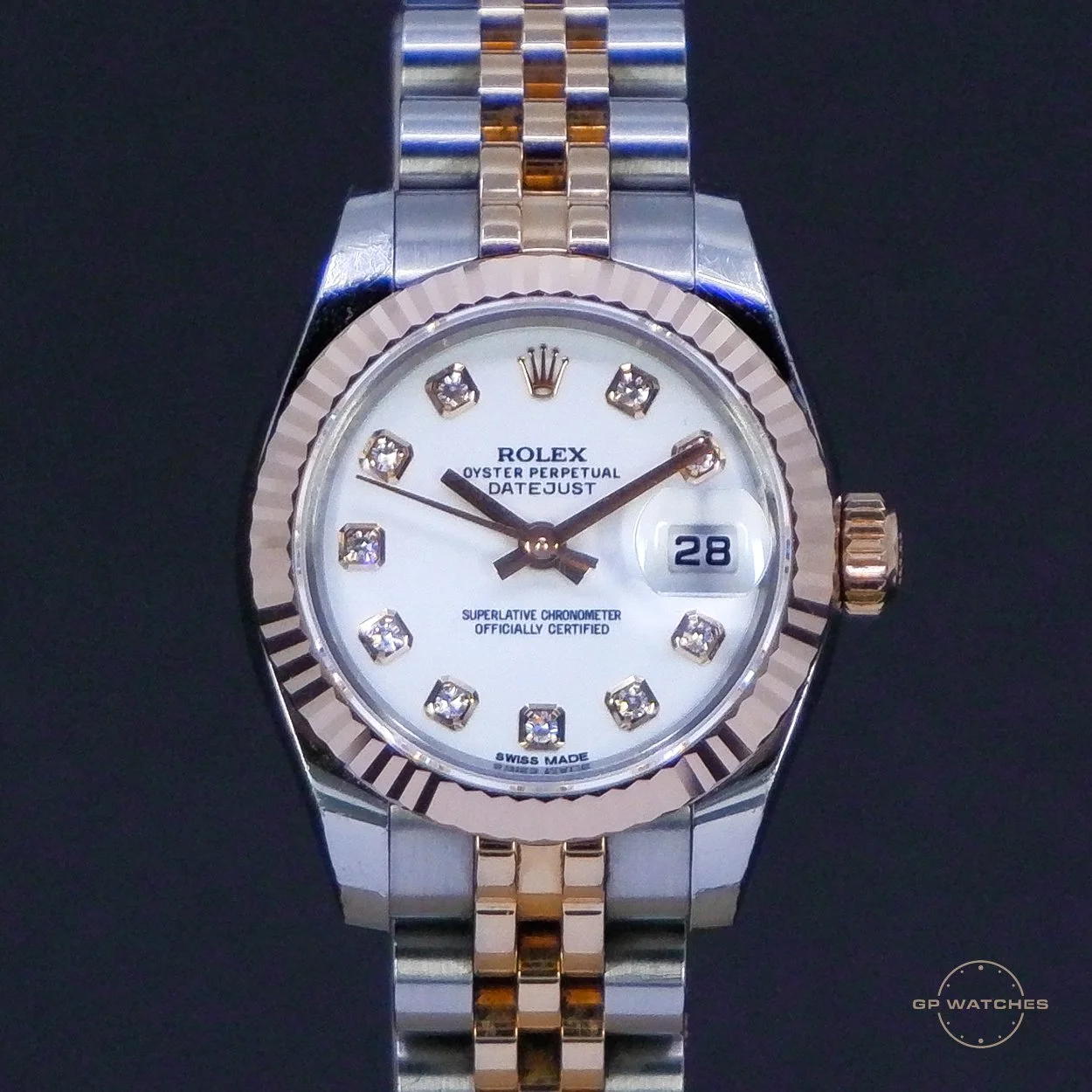 A two-tone Rolex Oyster Perpetual Datejust watch with a white dial, diamond hour markers, a date window at 3 o'clock, and a fluted bezel.